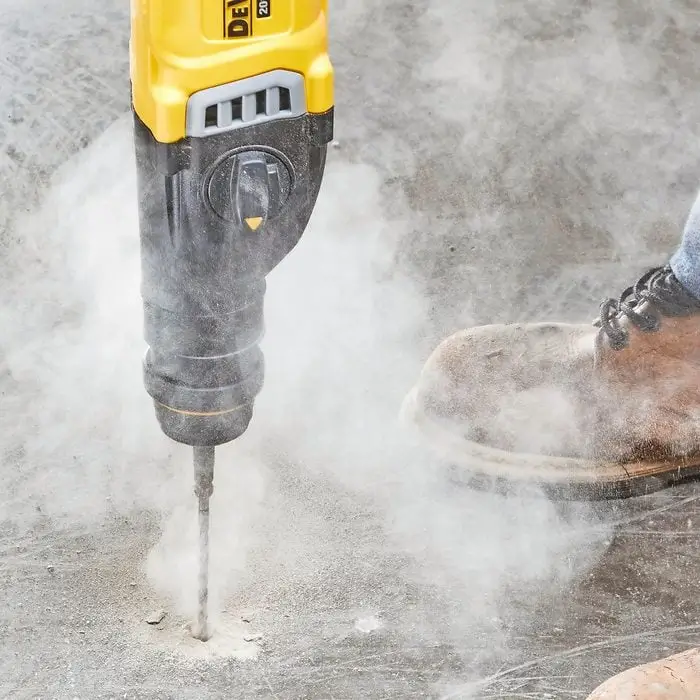 Worker using a drill on concrete, showcasing Concrete Cutters Auckland's services.